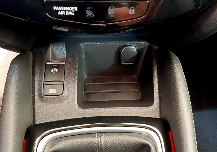 Gros plan sur la console centrale du Nissan Qashqai blanc 2019, avec frein à main électrique et bouton auto hold.