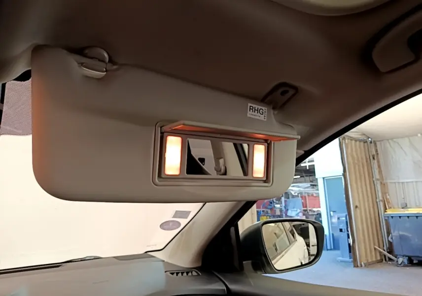 Détail de l'intérieur côté conducteur du Nissan Qashqai blanc 2019, miroir de pare-soleil éclairé avec rétro extérieur visible.