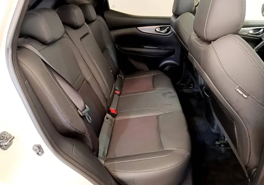 Vue côté gauche sur la banquette arrière noire du Nissan Qashqai blanc, avec ceinture de sécurité et appuie-têtes visibles.