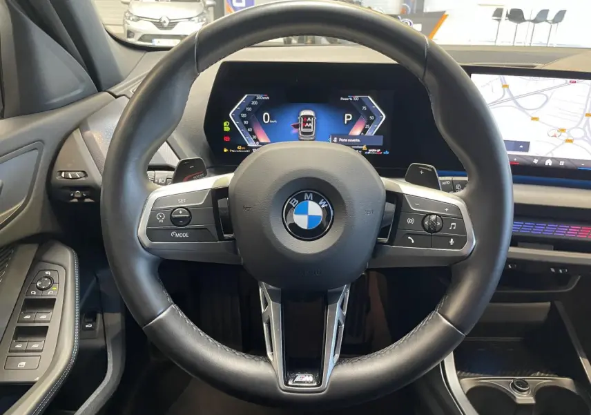 Vue intérieure centrée sur le volant cuir noir de la BMW Série 1 120d M Sport 2025 avec tableau de bord numérique.