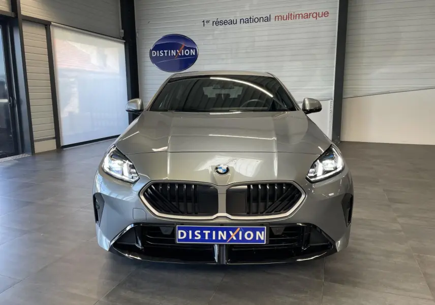 Vue frontale d'une BMW Série 1 120d M Sport gris métallisé avec calandre noire et phares allumés en showroom.