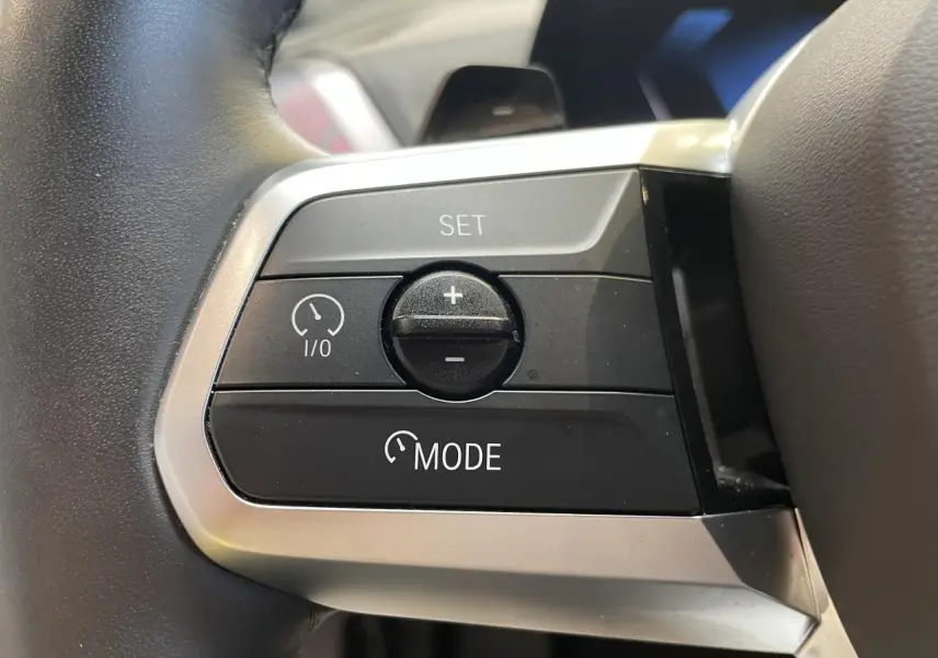 Gros plan sur les commandes de régulateur de vitesse au volant gris d'une BMW Série 1 120d M Sport 2025.