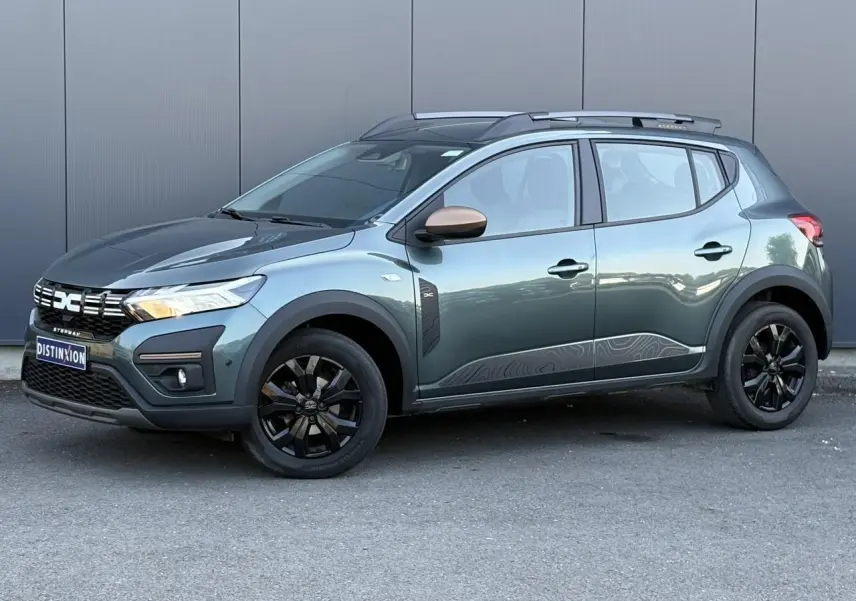 Dacia Sandero Stepway 2025 vert cèdre en 3/4 avant droit avec jantes noires et barres de toit grises.