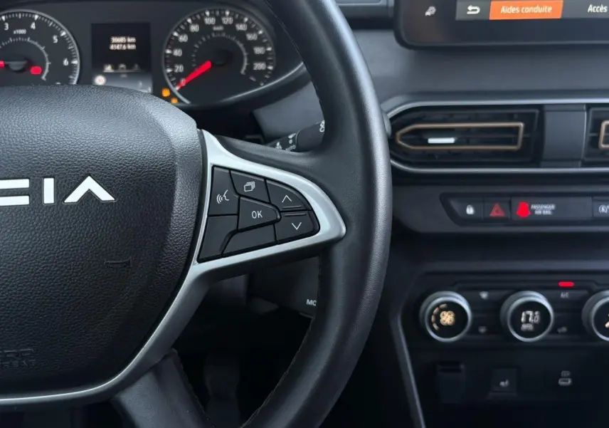 Gros plan sur le volant et tableau de bord de la Dacia Sandero Stepway 2025, avec commandes au volant et écran tactile visible.