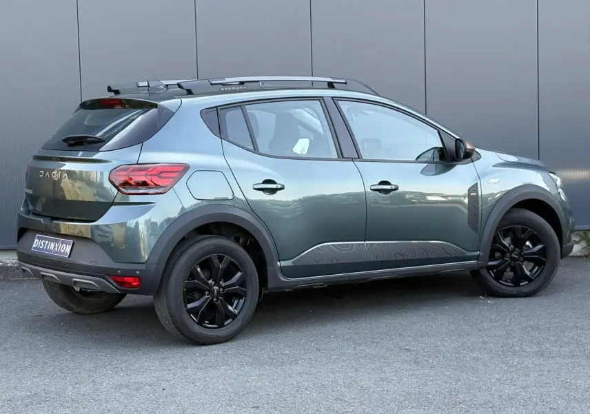 Vue latérale droite d'une Dacia Sandero Stepway 2025 Vert Cèdre avec jantes noires et barres de toit gris Mégalithe.