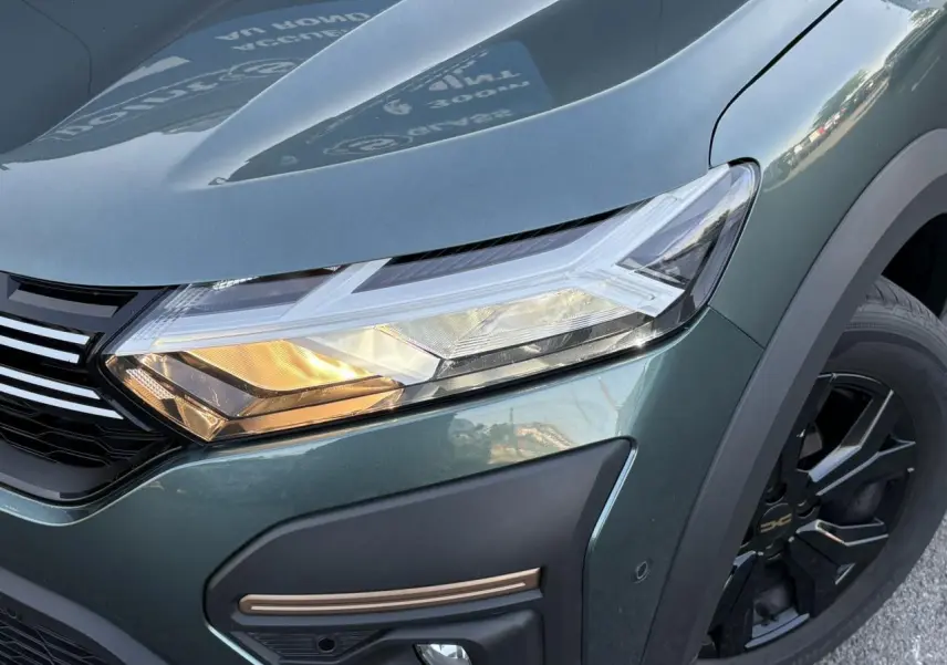 Gros plan sur l'avant droit vert cèdre du Dacia Sandero Stepway 2025 avec phare LED et jante aluminium noire.