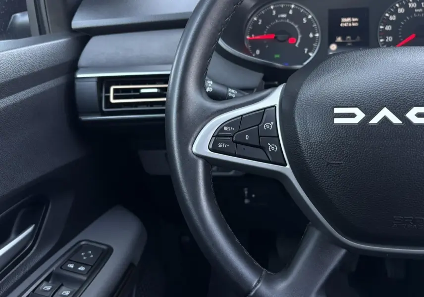 Vue intérieure rapprochée du volant noir Dacia Sandero Stepway avec commandes au volant et tableau de bord partiel.