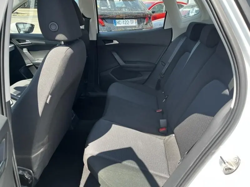 Vue intérieure côté droit des sièges arrière noirs du SEAT Arona blanc 2024, avec porte ouverte et lumière naturelle.