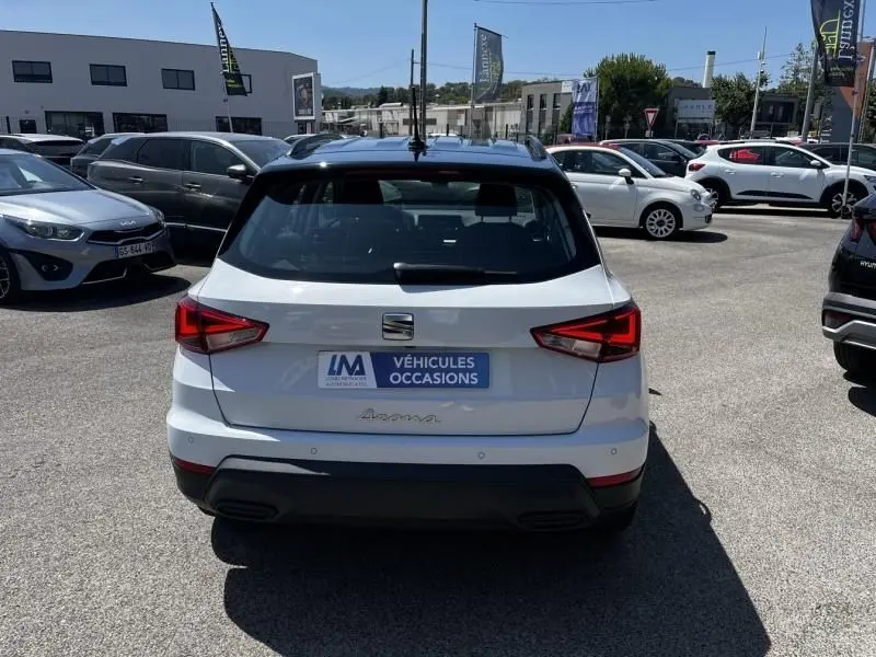 Vue arrière d'un SEAT Arona blanc 2024 avec feux LED et badge Arona visible sur un parking extérieur.
