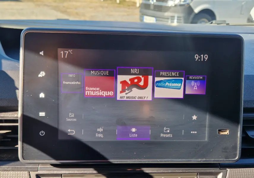 Écran tactile central du Renault Kangoo blanc 2023 affichant les stations radio avec interface moderne et commandes visibles.