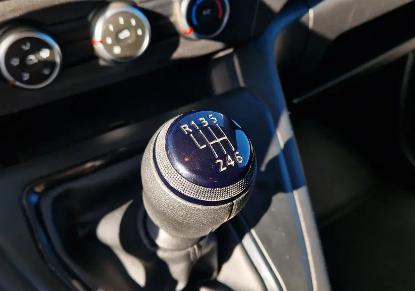 Gros plan sur le levier de vitesses manuel noir du Renault Kangoo 2023, avec commandes de climatisation en arrière-plan.