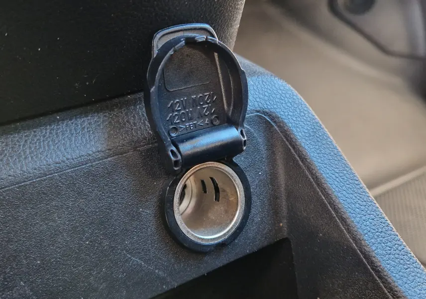 Prise 12V ouverte en gros plan dans l'habitacle noir du Renault Kangoo Van blanc 2023, côté conducteur.