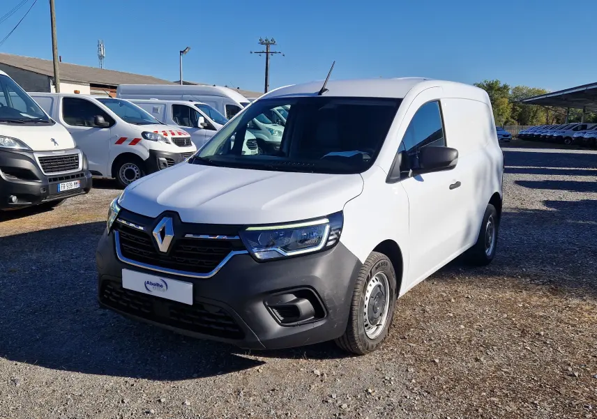 Renault Kangoo Van blanc en 3/4 avant droit, avec pare-chocs noir et calandre chromée, stationné en extérieur.