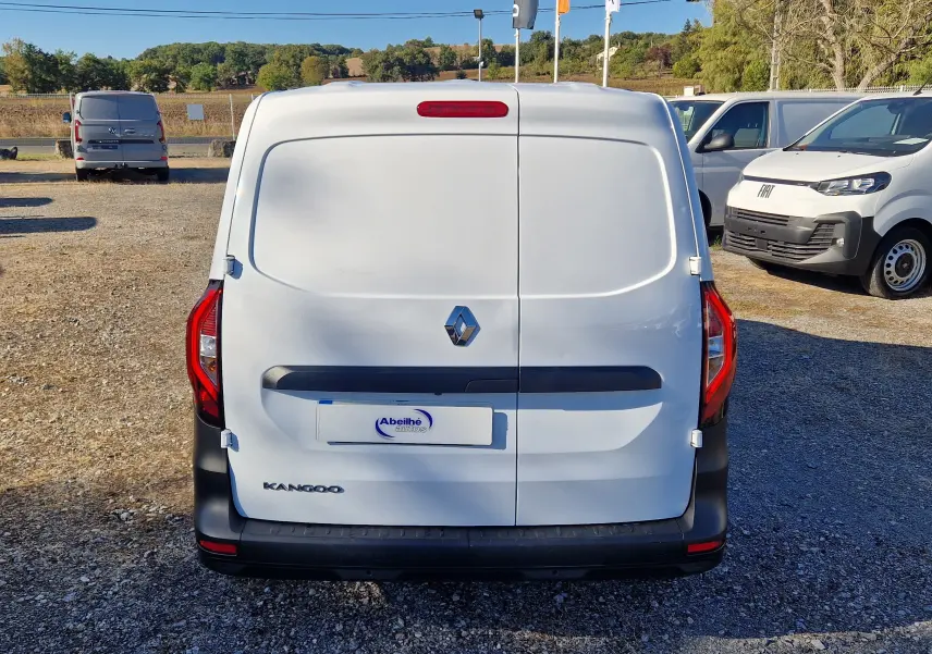 Vue arrière d’un Renault Kangoo blanc 2023, fourgon utilitaire avec portes battantes fermées sur un parking extérieur.