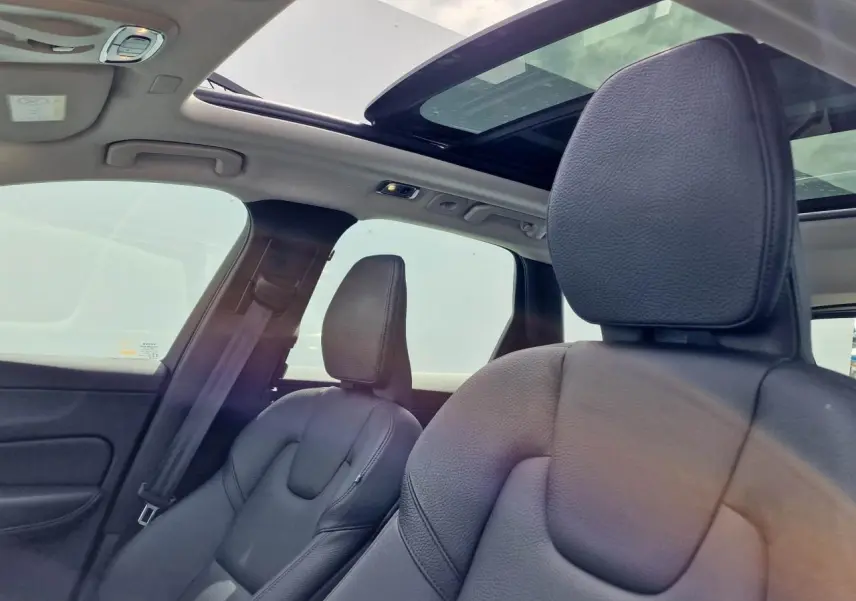 Intérieur du Volvo XC60 noir, vue sur sièges avant cuir et toit ouvrant panoramique lumineux.