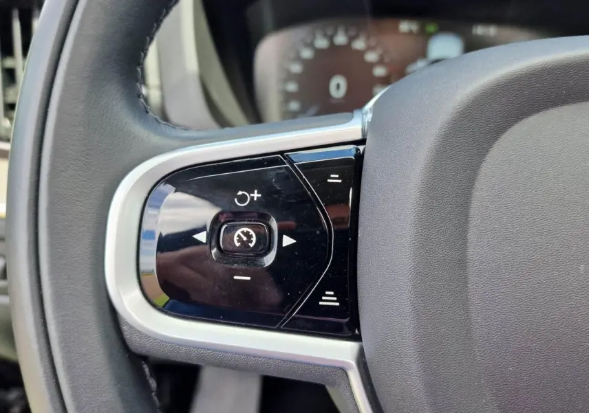 Gros plan sur les commandes de régulateur de vitesse au volant cuir noir du Volvo XC60 II Recharge T6 2021.