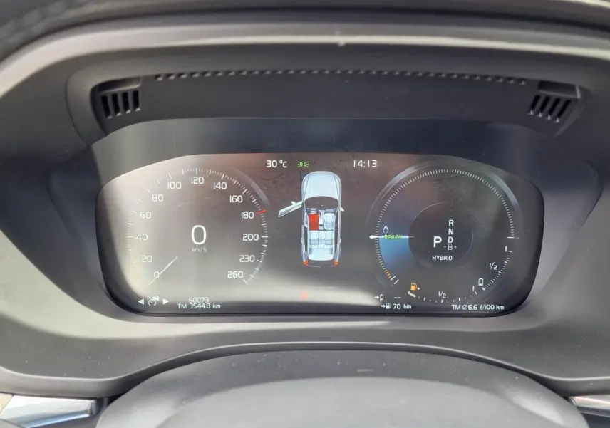 Combiné d'instruments digital du Volvo XC60 noir, affichant vitesse, mode hybride et portes ouvertes, vue de face.