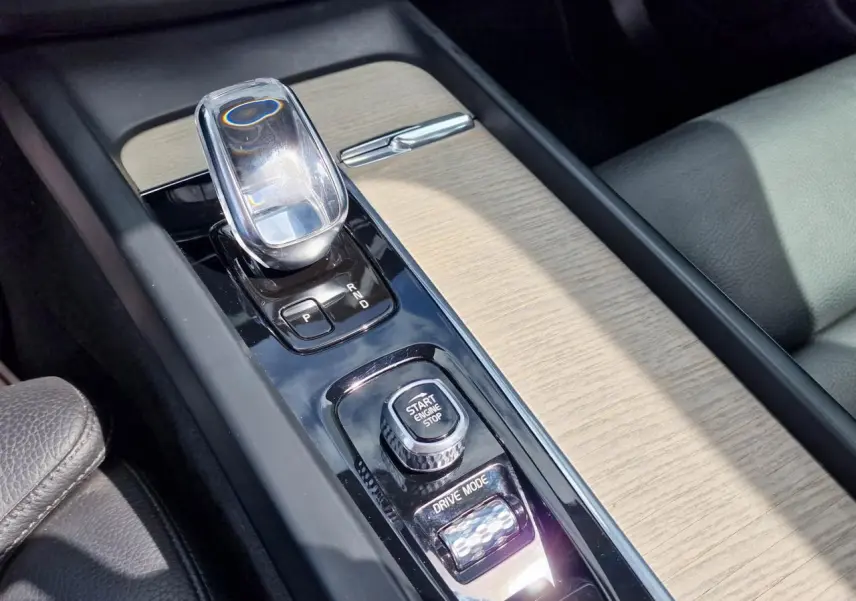 Gros plan sur la console centrale du Volvo XC60 noir, mettant en valeur le levier de vitesses en cristal et les commandes Start/Stop et Drive Mode.