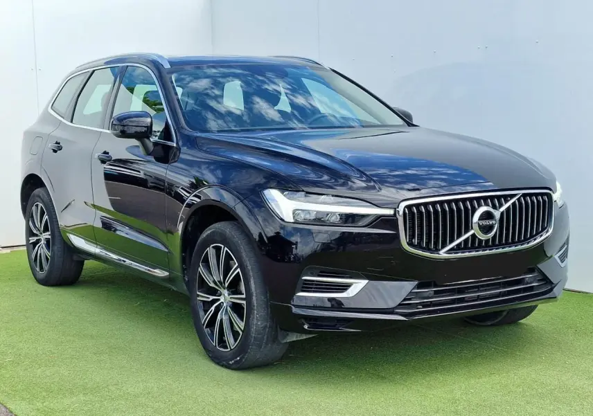 Volvo XC60 noir en 3/4 avant droit, avec calandre chromée et jantes alliage 19 pouces sur fond clair.