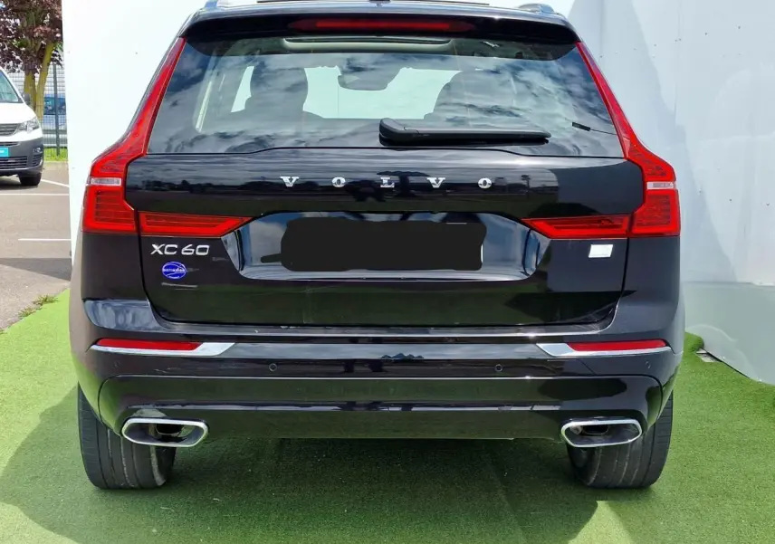 Vue arrière d'un Volvo XC60 noir avec feux arrière en forme de L et double sortie d'échappement chromée.