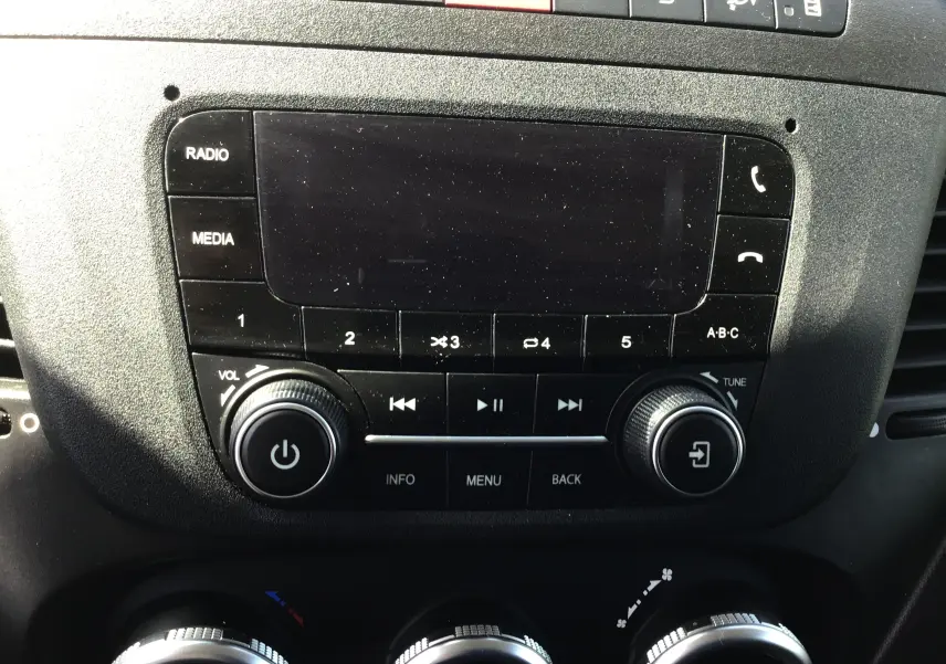 Gros plan sur la console centrale noire du tableau de bord de l'Iveco Daily Fourgon blanc, avec commandes radio et climatisation.