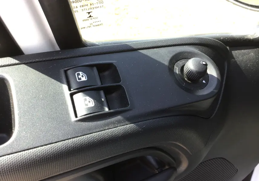 Gros plan sur les commandes électriques des vitres et rétroviseurs côté conducteur du fourgon blanc Iveco Daily 2022.
