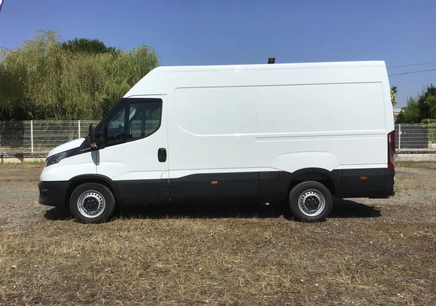 Fourgon Iveco Daily blanc vu de profil côté gauche, avec bas de caisse noir et jantes acier simples.
