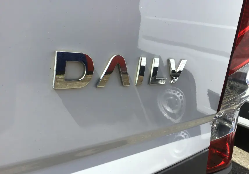 Gros plan sur l'arrière droit blanc d'un Iveco Daily Fourgon 2022 avec logo chromé et feu arrière rouge visible.