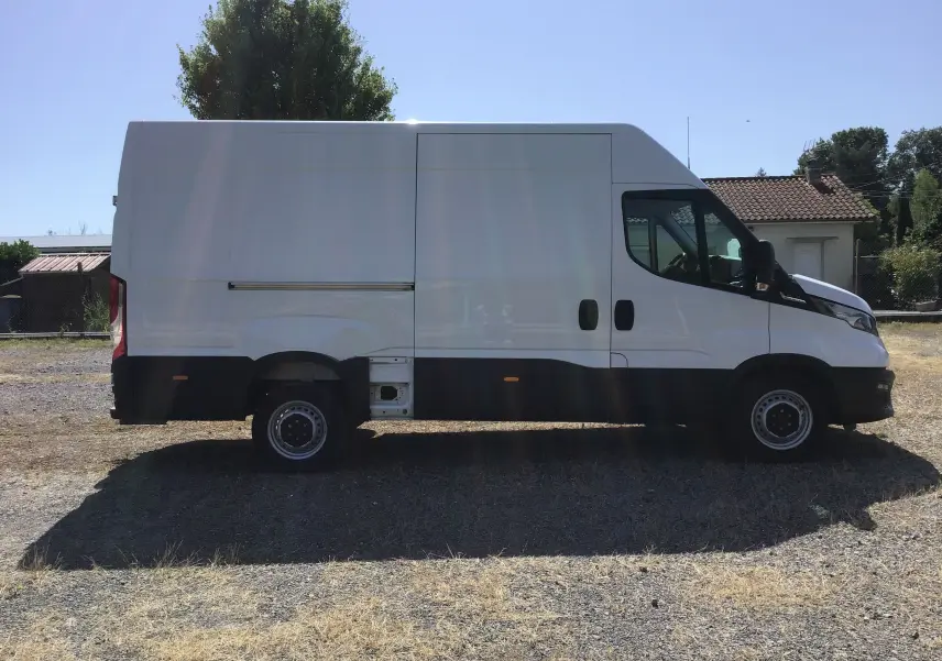 Profil latéral droit d'un fourgon blanc Iveco Daily 2022 avec porte coulissante et marchepied arrière visible.