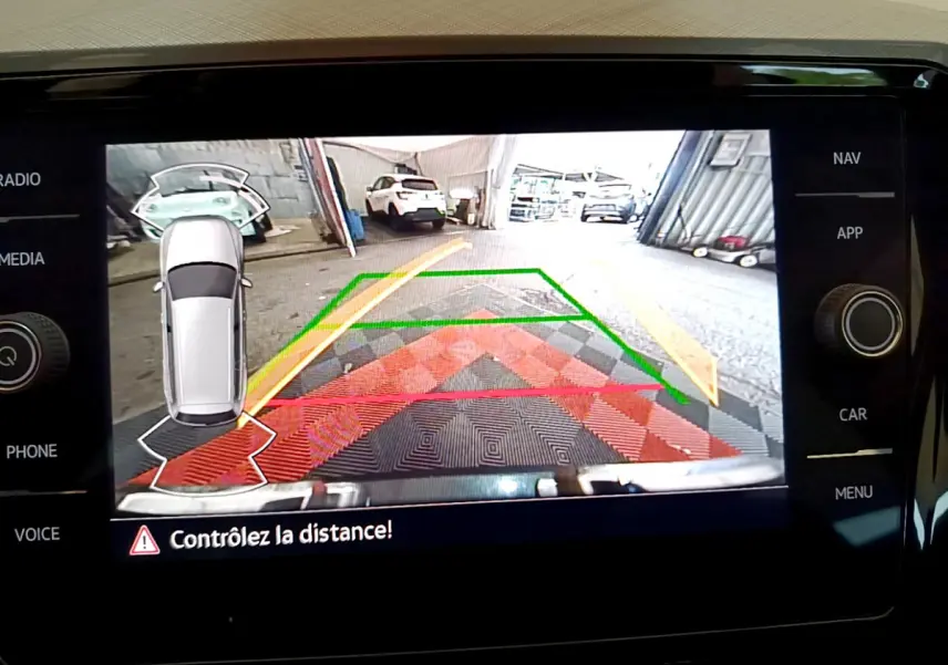 Affichage caméra de recul avec guidage coloré sur écran tactile du tableau de bord d'une Volkswagen Passat gris foncé.