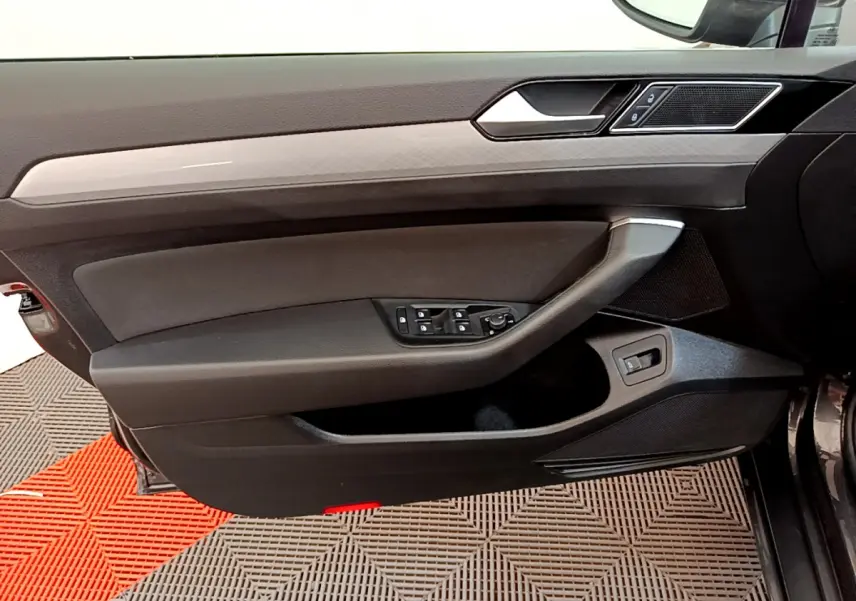 Vue rapprochée de la porte avant gauche intérieure noire de la Volkswagen Passat 2.0 TDI 2021 avec commandes électriques.