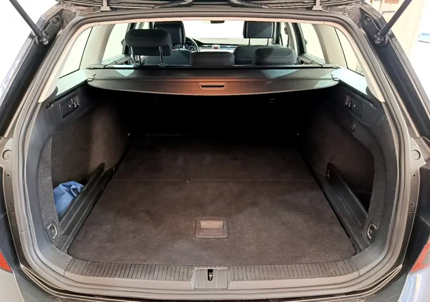 Coffre ouvert d'une Volkswagen Passat gris foncé, vue arrière, montrant l'espace de chargement avec tablette de séparation.