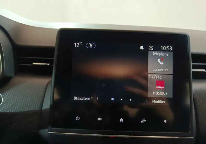 Écran tactile central du tableau de bord de la Renault Clio Business TCe 90 blanc, affichant téléphone et musique