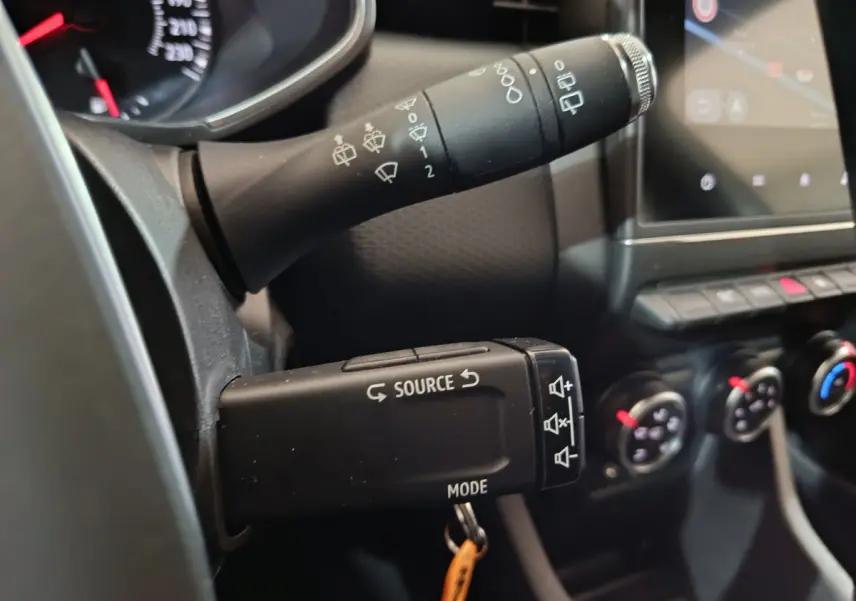 Gros plan sur les commandes au volant de la Renault Clio Business TCe 90 blanc, avec tableau de bord et écran tactile visibles.
