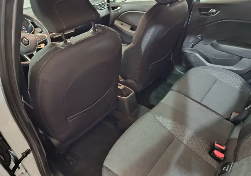 Vue intérieure arrière côté droit de la Renault Clio Business blanche, montrant la banquette arrière noire et les dossiers des sièges avant.