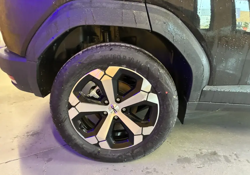 Gros plan sur la roue arrière droite du Dacia Duster 1.6 Hybrid 140 Journey noir, avec jante alliage bicolore moderne.