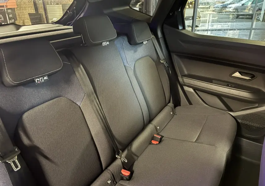 Vue intérieure côté droit des sièges arrière noirs en tissu du Dacia Duster 1.6 Hybrid 140 Journey 2025 avec appuie-têtes et ceintures.