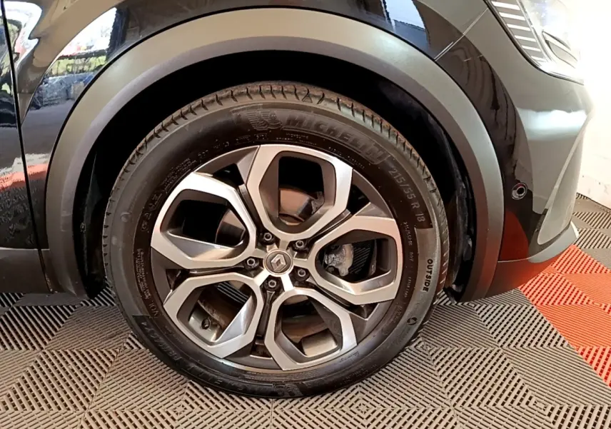 Gros plan sur la roue avant droite du Renault Captur noir 2021 avec jante alliage et logo Renault au centre.