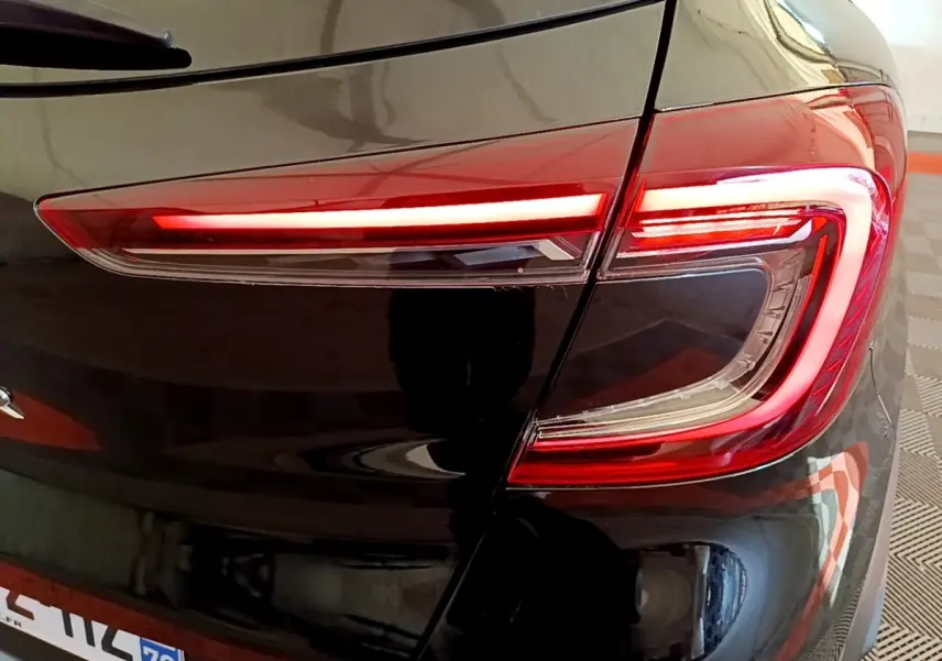 Gros plan sur le feu arrière droit rouge et blanc du Renault Captur Business noir, soulignant la finition moderne et brillante.