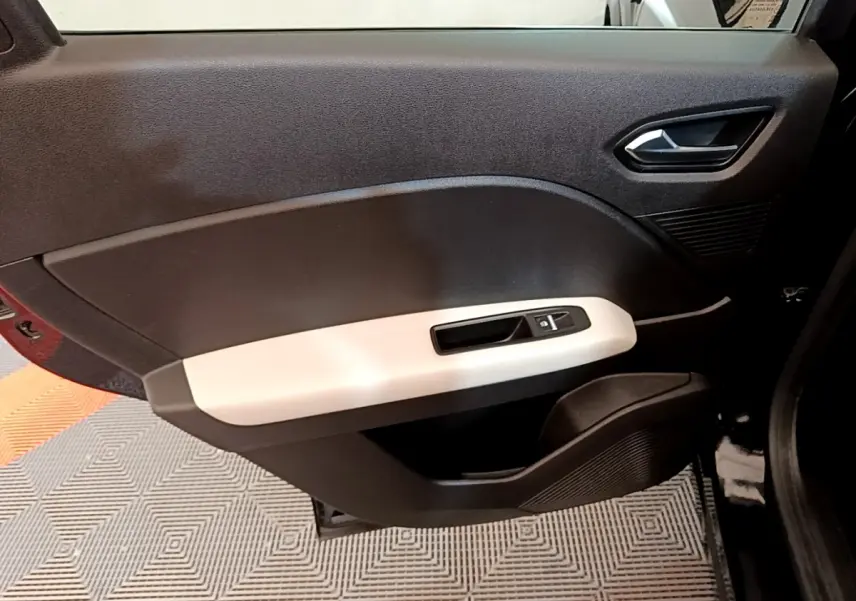 Vue rapprochée de la porte intérieure côté gauche du Renault Captur Business noir, avec poignée argentée et commande de vitre.