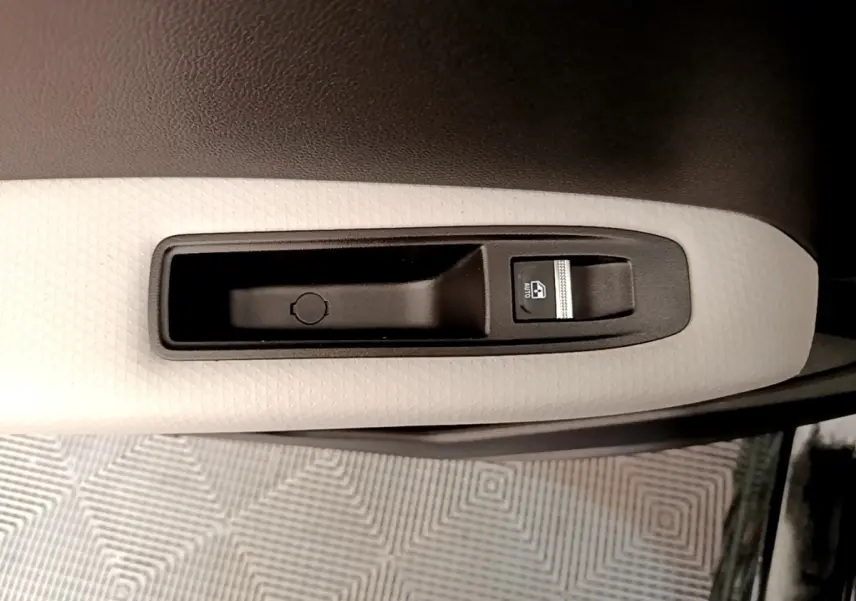 Gros plan sur la commande de lève-vitre côté conducteur du Renault Captur Business noir, avec insert blanc texturé.