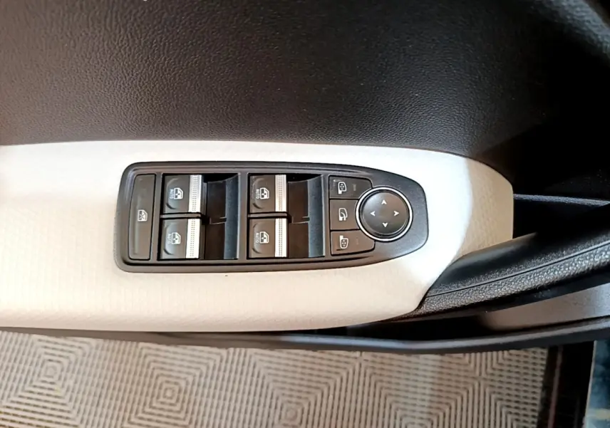 Gros plan sur les commandes de lève-vitres et réglage des rétroviseurs sur la portière côté conducteur du Renault Captur noir.