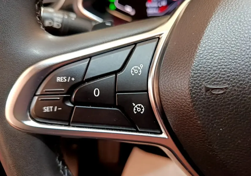 Gros plan sur les commandes noires du régulateur de vitesse à gauche du volant du Renault Captur Business 2021.