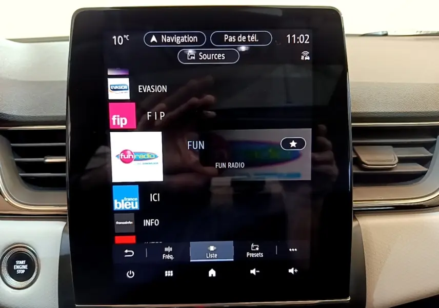 Écran tactile central du tableau de bord du Renault Captur Business noir, affichant les stations radio avec bouton démarrage visible.