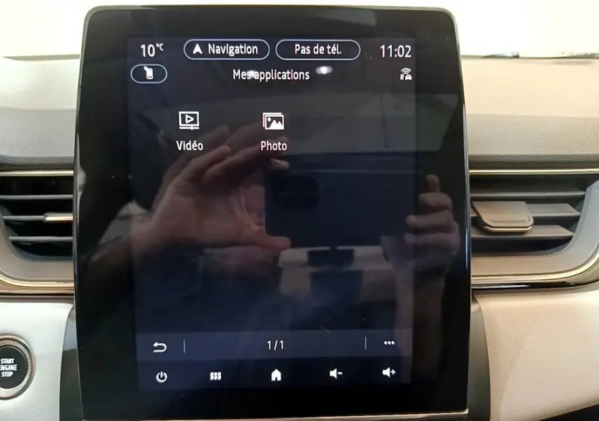 Gros plan sur l'écran tactile central du tableau de bord du Renault Captur Business noir, avec affichage des applications vidéo et photo.
