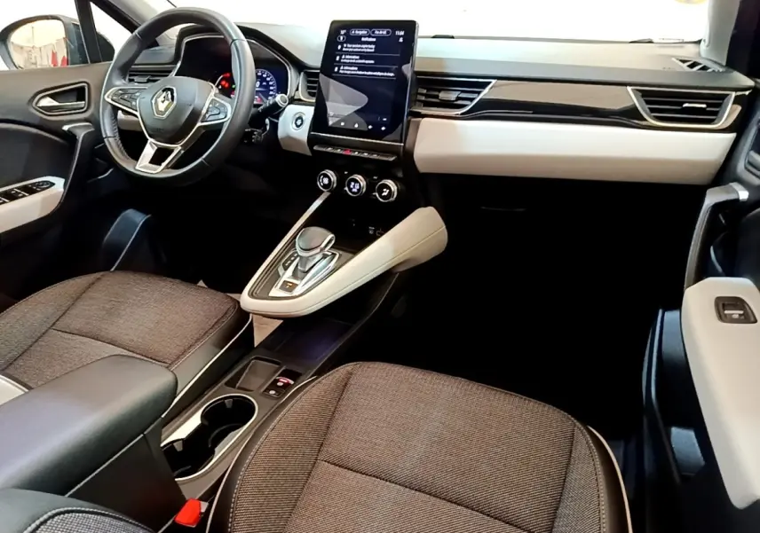 Vue intérieure avant droite du Renault Captur Business 2021, tableau de bord clair avec écran tactile vertical et sièges gris.