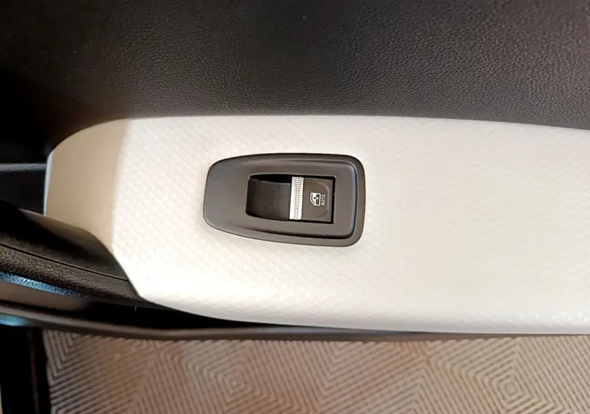 Gros plan sur le bouton de commande de lève-vitre avant droit, intérieur blanc texturé du Renault Captur noir 2021.