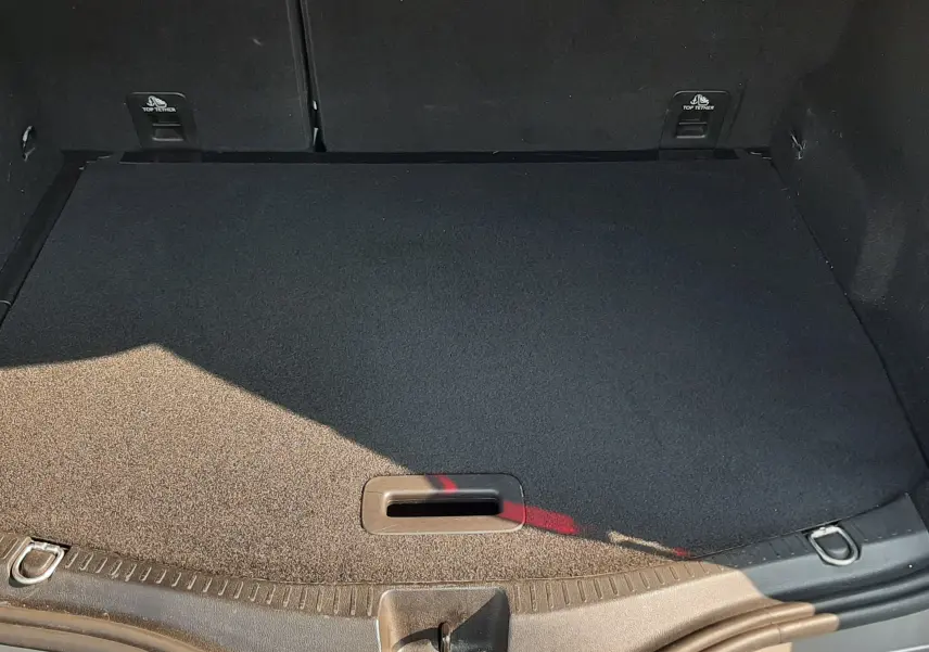 Coffre ouvert du Renault Scénic IV gris Cassiopée avec tapis noir et fixations visibles, vue de dessus.