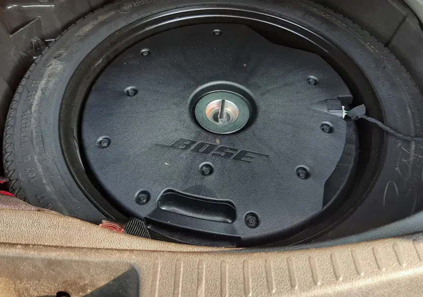 Vue rapprochée du caisson de basse Bose intégré dans la roue de secours du coffre d’un Renault Scénic IV gris.