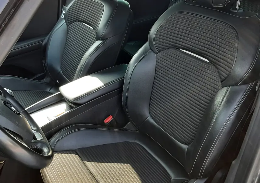 Vue intérieure rapprochée des sièges avant en cuir noir avec surpiqûres blanches du Renault Scénic IV gris cassiopée.